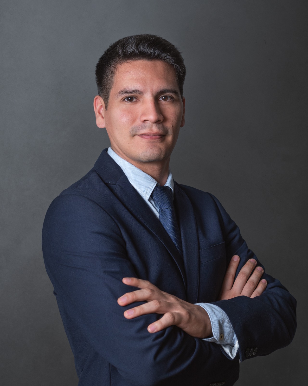 Retrato del Dr. José León, neurocirujano, con traje oscuro y brazos cruzados